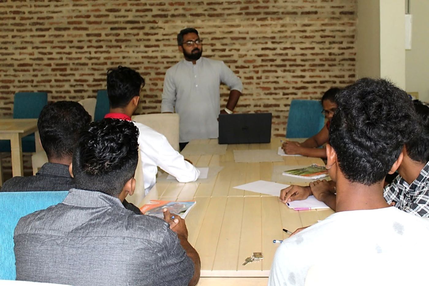 Arqam Azhar leading a small-group workshop around a shared table