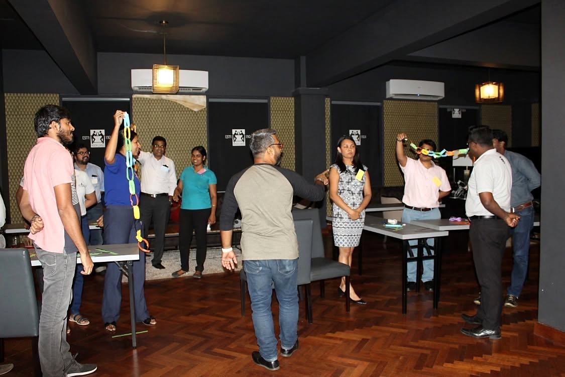 Participants on their feet during a hands-on team activity with paper chains
