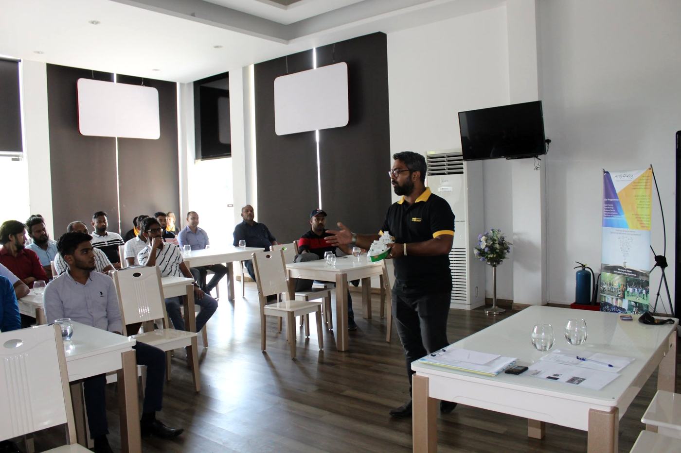 Arqam Azhar facilitating a session next to an Arqi-Ology banner